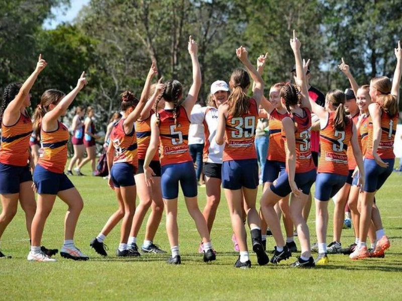 A girls sports team standing in a circle with their arms raised