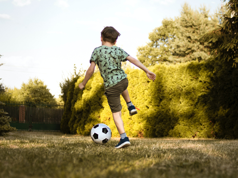 a young child kicking a soccer ball in the backyard